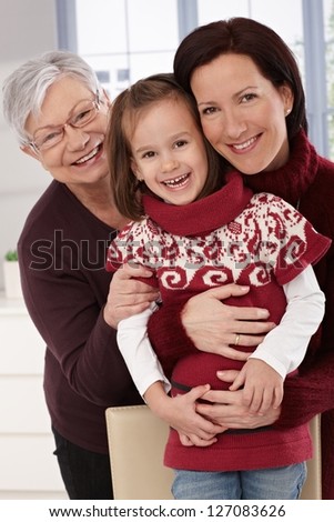 Grandmother, mother and daughter smiling, hugging.
