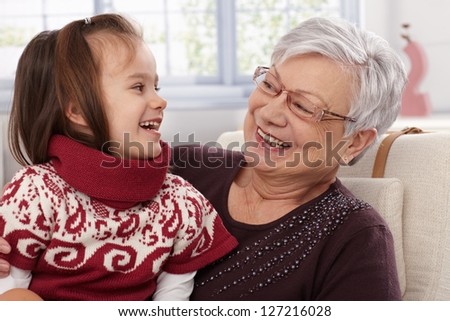 Grandmother and granddaughter laughing, looking at each other.