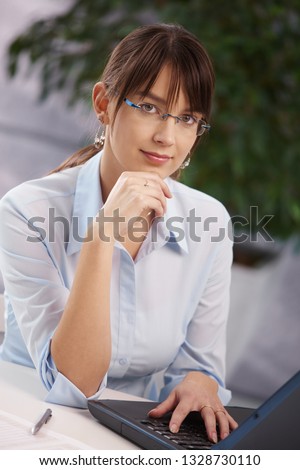 Business portrait - woman working with computer at office desk.
