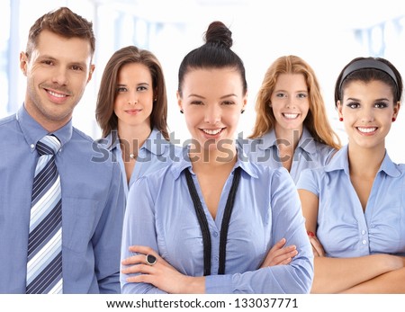 Team portrait of happy office workers wearing uniform, looking at camera smiling.