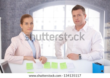 Casual office workers standing in bright office.