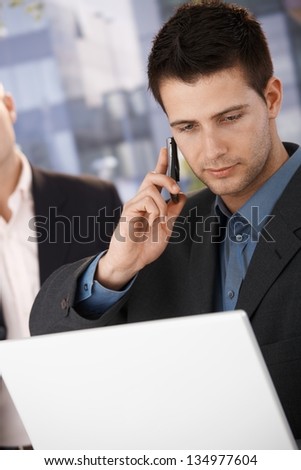 Businessman on mobile phone call holding laptop computer outside of office.