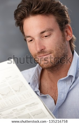 Portrait of goodlooking smiling man reading newspaper.