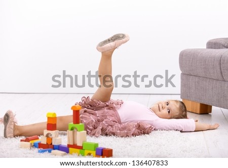 Little ballerina girl laying on floor at home, playing, posing.