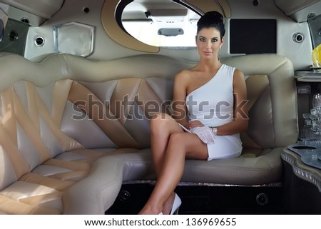 Beautiful elegant woman sitting in luxury limousine.