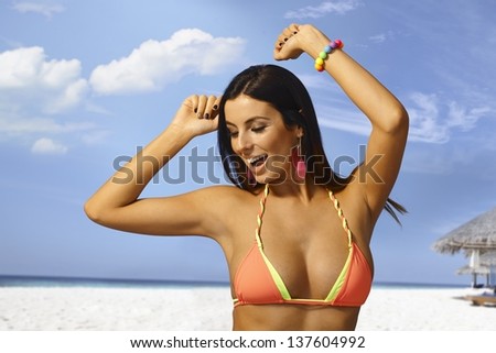 Beautiful young woman enjoying summer holiday on the beach in bikini, smiling happy, dancing in sunshine.