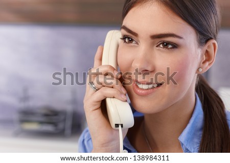 Happy young pretty woman on landline phone call, smiling.