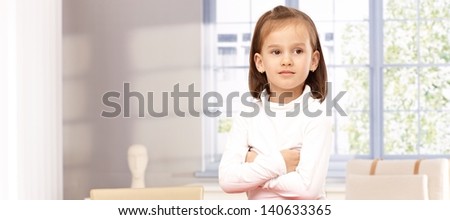 Cute little girl standing arms crossed, sulking, looking away.