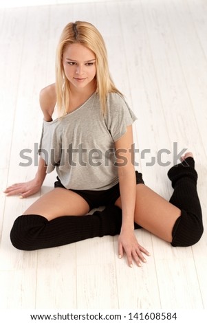 Pretty female dancer sitting on floor, looking down.