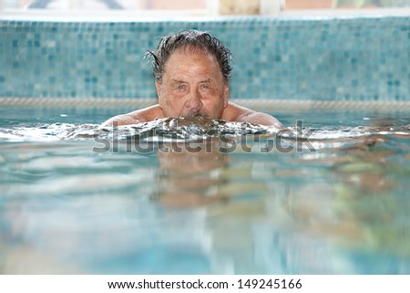 Elderly man swimming at swimming pool.