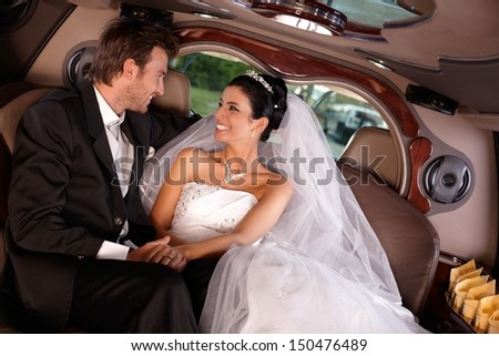 Happy young couple sitting in limousine on wedding day.