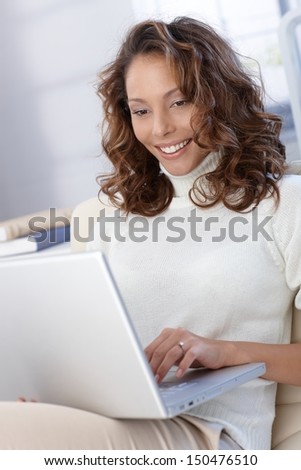 Happy woman using laptop computer, working, browsing internet.