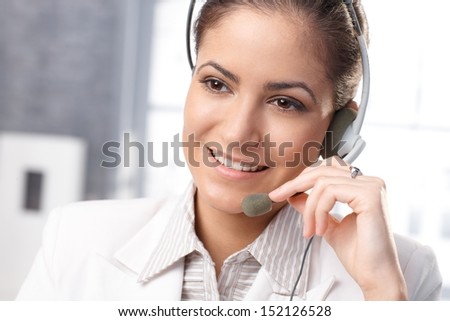 Closeup portrait of smiling customer service representative using headset, hand on microphone.
