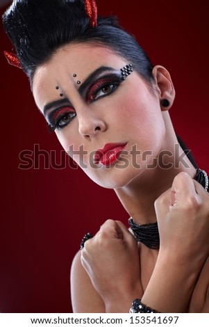 Closeup portrait of devil woman with clenched fists and professional makeup.