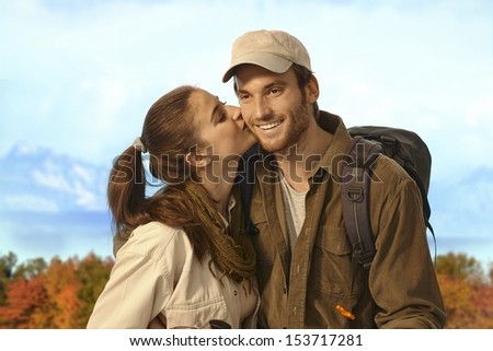 Happy young couple hiking together in nice autumn weather, woman kissing man.