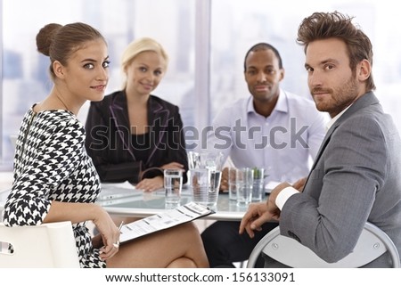Young businesspeople sitting at meeting table, having discussion.