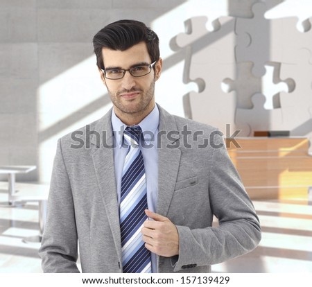 Confident businessman at office reception, puzzle decoration in background.