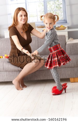 Little girl posing in mother\'s high heel red slippers, having fun.