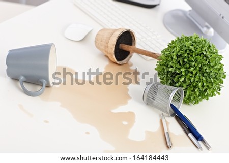 Mess on desk, overturned plant and mug, spilled out coffee.