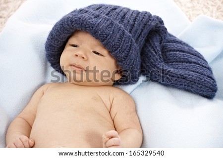 Lovely newborn baby lying naked in knitted hat.
