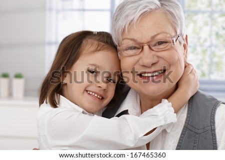 Cute little girl hugging grandmother, both smiling.
