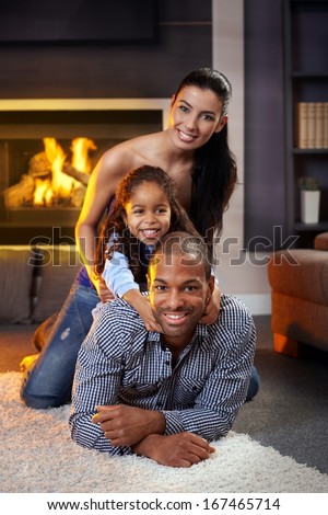Portrait of happy diverse family at home lying on each other, smiling.
