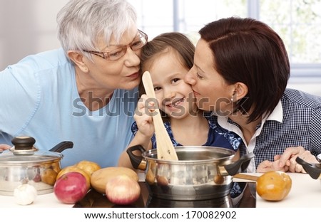 Mother, Grandmother And Little Daughter Cooking Together At Home, All Smiling.