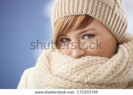 Attractive young woman covering her face with shawl on a cold winter day