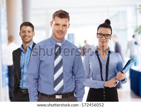 Portrait of happy young businesspeople at busy office.