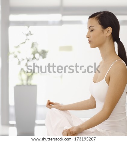 Young woman meditating eyes closed in yoga position indoors.