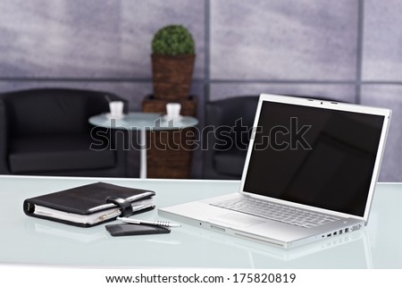 Closeup photo of laptop, personal organizer and mobilephone placed on desktop in office.