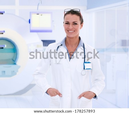 Happy middle-aged caucasian female doctor in MRI room at hospital.