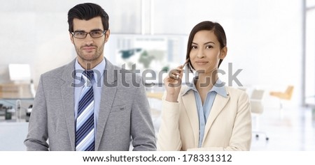 Portrait of international business couple at office, smiling.
