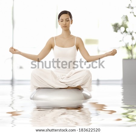 Young woman sitting in yoga position, relaxing eyes closed.