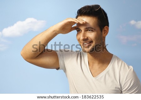 Happy young man looking at distance at summertime over blue sky.