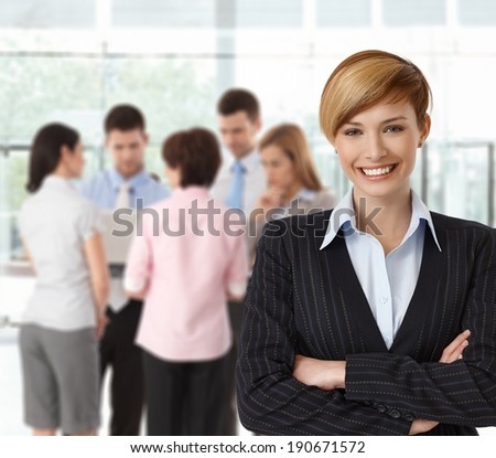Portrait if happy businesswoman with colleagues working in background.