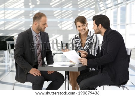 Happy corporate business people having discussion by coffee table.