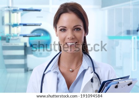 Happy female doctor looking at camera in MRI room of hospital.