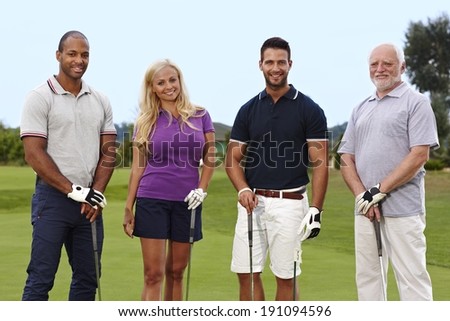 Happy group of golfers standing on the green, holding golf club.