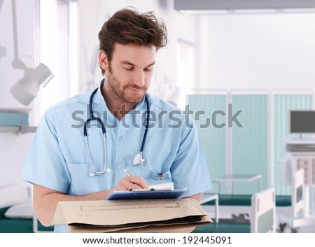 Doctor filling out patient record in hospital room.