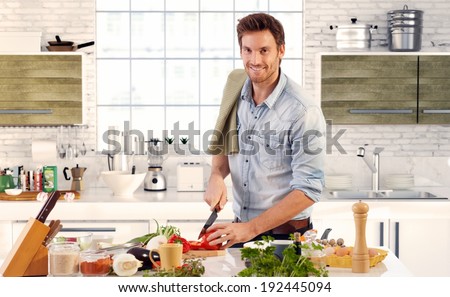 Happy handsome man cooking in kitchen at home.