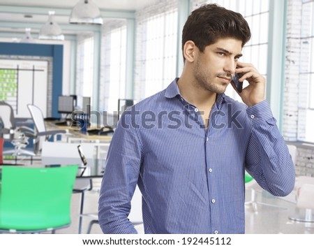 Casual man on the phone at work in modern office.