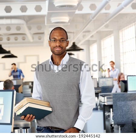 Intelligent black man at office holding books