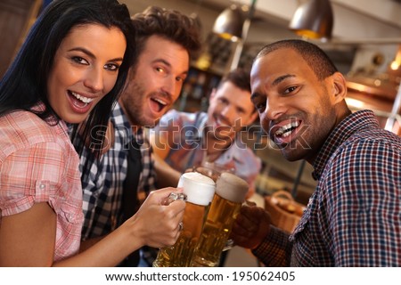 Group of happy young people drinking beer, having fun in pub, laughing.