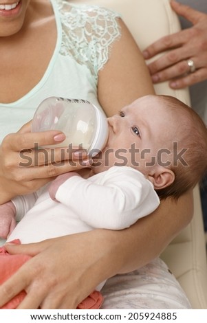 Closeup photo of newborn baby drinking milk from feeding bottle.