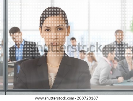 Asian businesswoman at busy office looking through window