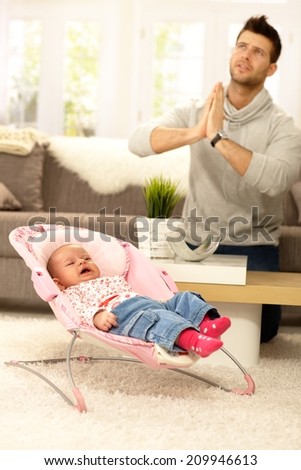 Young father praying for peace by crying baby.