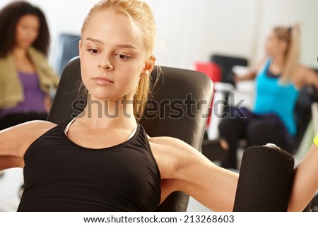 Fit girl exercising at the gym, doing arm exercises.