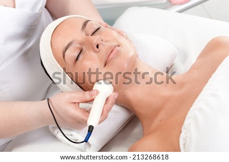 Young woman laying eyes closed, receiving facial beauty treatment in beauty saloon.