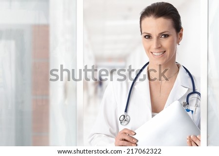 Portrait of happy female doctor smiling at hospital corridor.